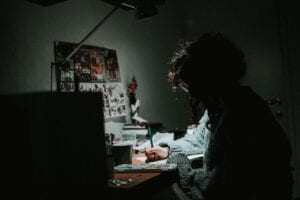 Girl writing at a desk in dim light.