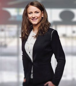 Young woman in a black blazer and white shirt smiling confidently.